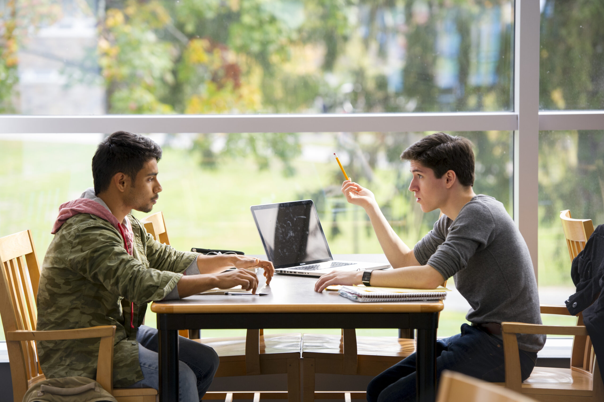 students sitting working together on laptop